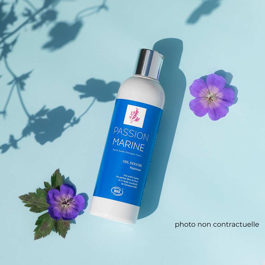 Bouteille de gel douche "Passion Marine" sur fond bleu avec fleurs violettes.