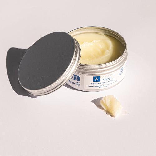 Boîte ouverte de beurre corporel avec couvercle et morceau de beurre.