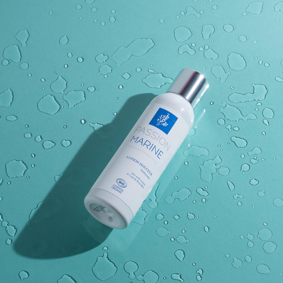 Bouteille de lotion Passion Marine sur fond bleu avec gouttes d'eau.