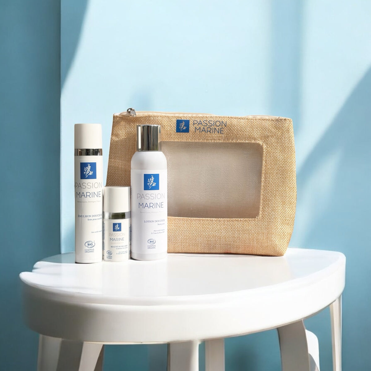 Produits Passion Marine sur une table blanche avec pochette beige, fond bleu.