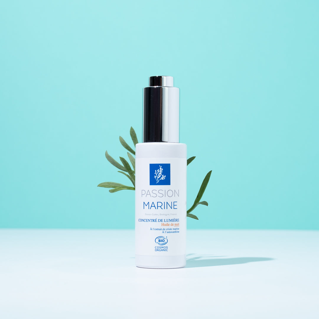Flacon d'huile Passion Marine sur fond bleu avec feuilles vertes.