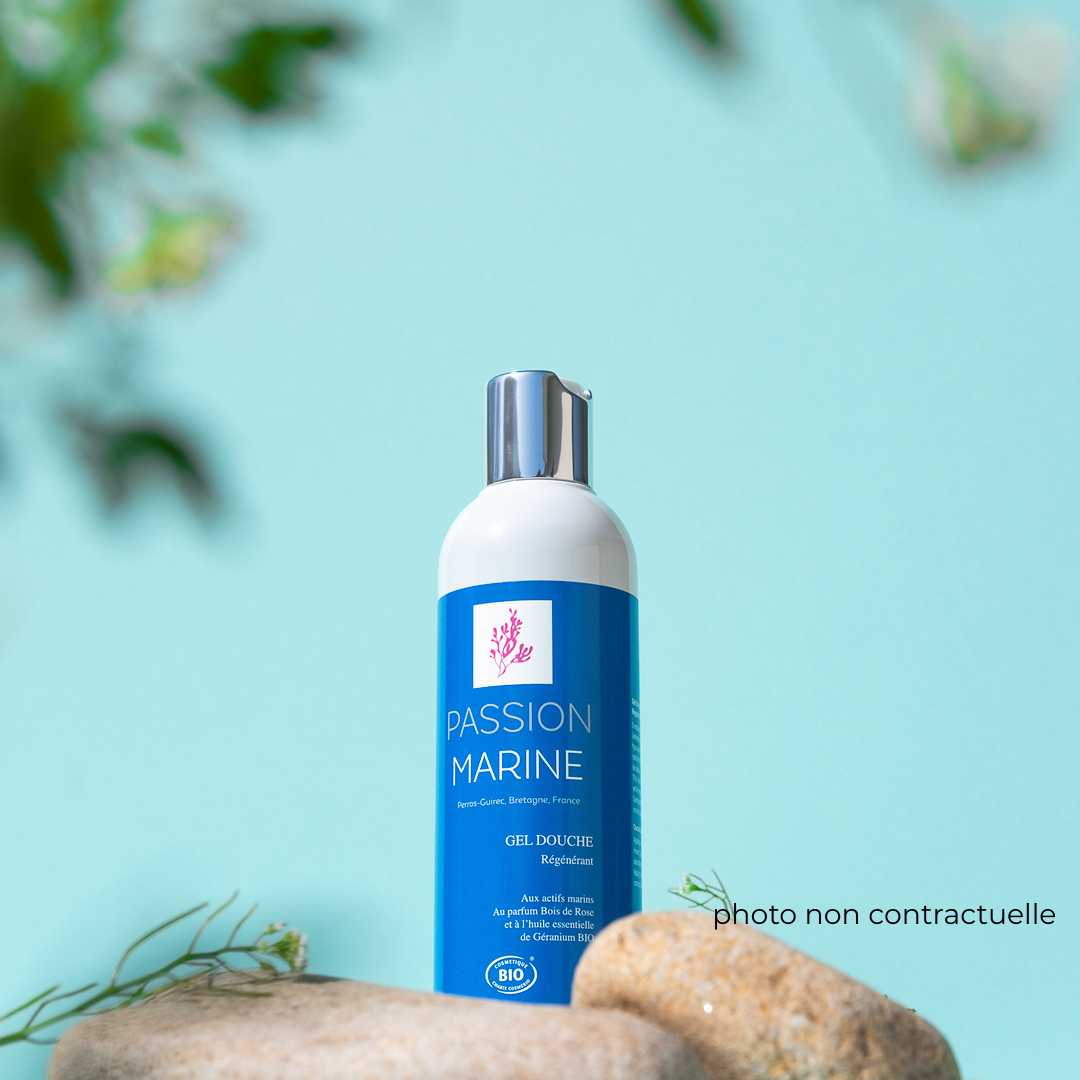 Bouteille de gel douche Passion Marine sur fond bleu avec pierres au premier plan.